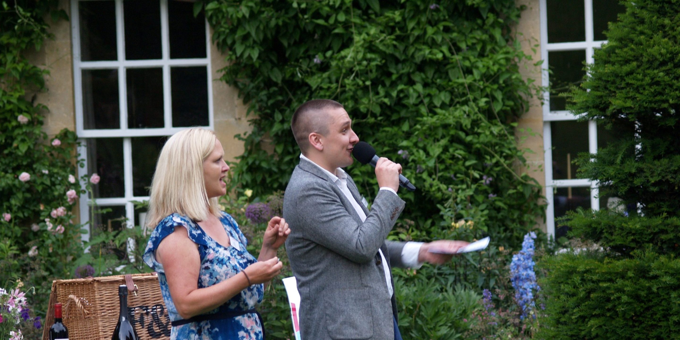 Man and woman laughing, giving out raffle prizes. Man is holding a microphone