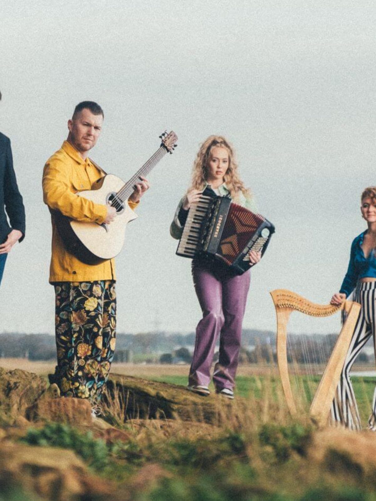 Four people standing a field holding instruments