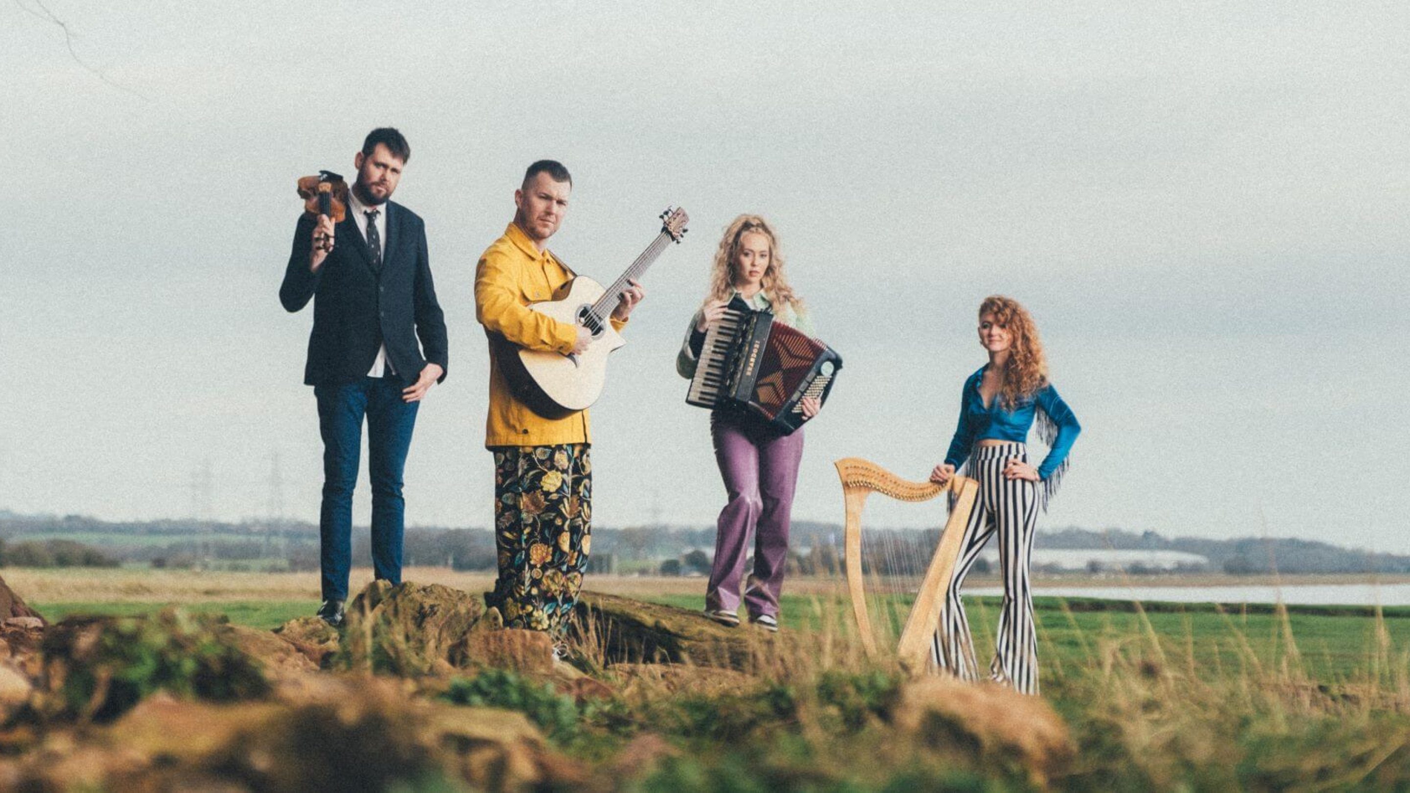 Four people standing a field holding instruments